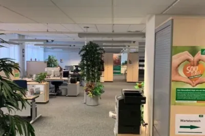 "Einrichtung AOK Neheim: Büro mit Arbeitsplätzen, Pflanzen und Werbeverteilern"