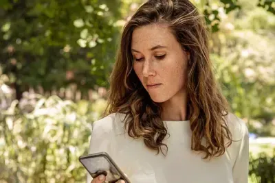 Frau schaut auf ihr Handy, um Bonusprogramm der AOK zu überprüfen