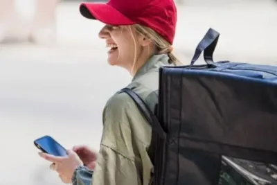 DBK Krankenkasse Kontakt Service: So erreichen Sie schnell und direkt Ihren Ansprechpartner 9 "Frau mit rotem Cap und schwarzem Rucksack sitzt auf Fahrrad und schaut aufs Handy"