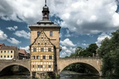 AOK Bamberg: Adresse, Öffnungszeiten & Kontakt zum Kundencenter 6 "Historischer Turm am Flussufer, Brücke und Fachwerkhaus in Bamberg"