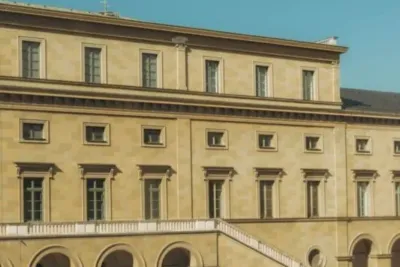 Deutsches Schulgebäude mit deutscher Flagge vor blauem Himmel, Symbol für Bildung und Abitur in Deutschland.