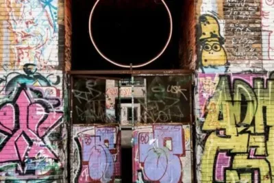Graffiti an einer Wand mit offenem Durchgang und orangem Kreis, Berlin.