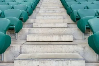 TK Krankmeldung online einreichen in 3 Minuten: Schritt-für-Schritt-Anleitung für eine schnelle und einfache Krankschreibung bei der Techniker Krankenkasse 3 "Leere Sitzreihen mit grünen Sitzen in einem Stadion mit Betonstufen, Eingang im Hintergrund"