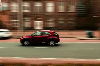 Ein rotes Auto fährt schnell über eine Straße, symbolisch für den Weg zurück zur Fitness nach einer Kreuzband-OP.