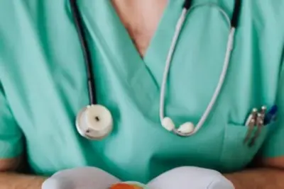 Fachwirt im Gesundheits- und Sozialwesen: Fernstudium Kosten, Dauer & IHK-Prüfung 6 Gesundheitspfleger mit Schutzkleidung hält Münzen und Geldscheine, Symbolbild Fachwirt im Gesundheits- und Sozialwesen Kost