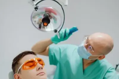 Zahnzusatzversicherung mit 100% Kostenübernahme: Lohnt sich das wirklich? 5 Zahnarztbehandlung: Patient im Behandlungsstuhl mit Schutzbrille, Zahnarzt mit Schutzmaske und Handschuhen.