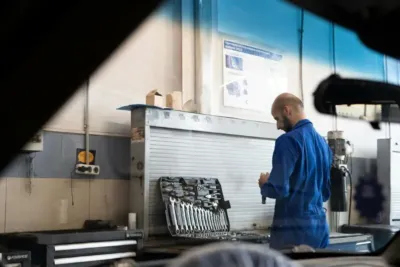 AOK Nordost Servicecenter Wedding - Schneller Service ohne Warteschleifen bei der Krankenkasse 4 Mann in blauer Arbeitskleidung im Werkstattbereich mit Werkzeug